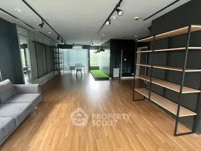 Spacious modern living room with sleek wooden flooring and stylish shelving unit.