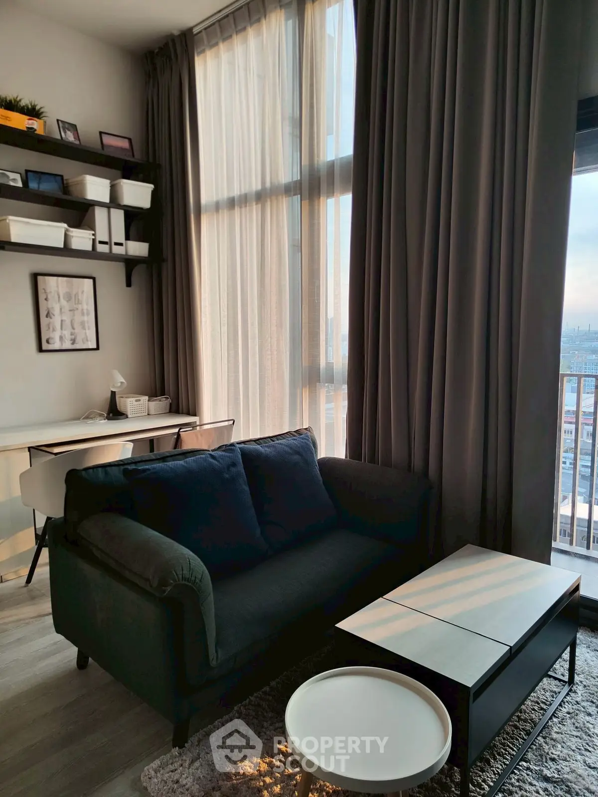 Modern living room with high ceilings, large windows, and stylish furniture in a city apartment.