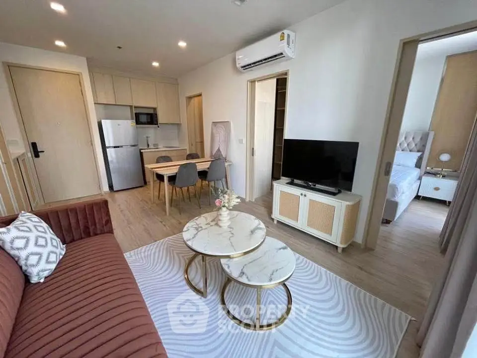 Modern open-plan living room with stylish furniture and kitchen area in a contemporary apartment.