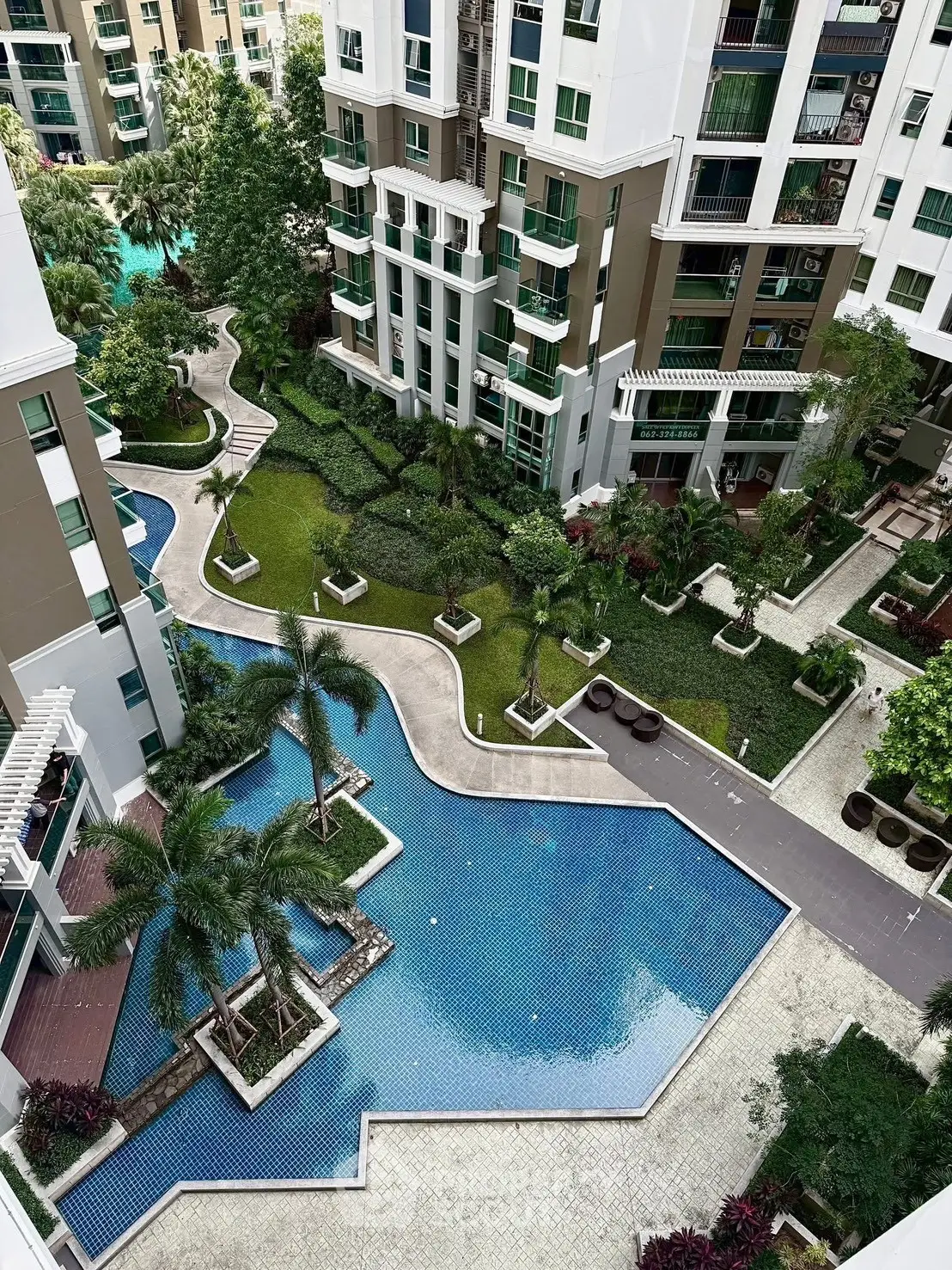 Luxurious residential complex with stunning pool and lush garden views.