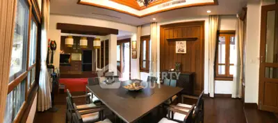 Elegant dining area seamlessly connects to a cozy living space, featuring rich wooden finishes and modern lighting, perfect for entertaining.