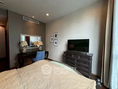 Elegant bedroom with stylish furniture and large TV, perfect for relaxation.