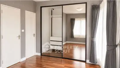 Spacious bedroom with mirrored closet and elegant hardwood flooring