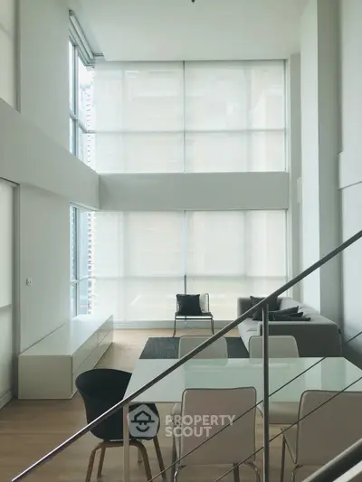 Spacious modern living room with high ceilings and large windows in a luxury apartment.