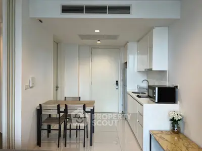 Modern kitchen with dining area in sleek apartment, featuring minimalist design and compact layout.