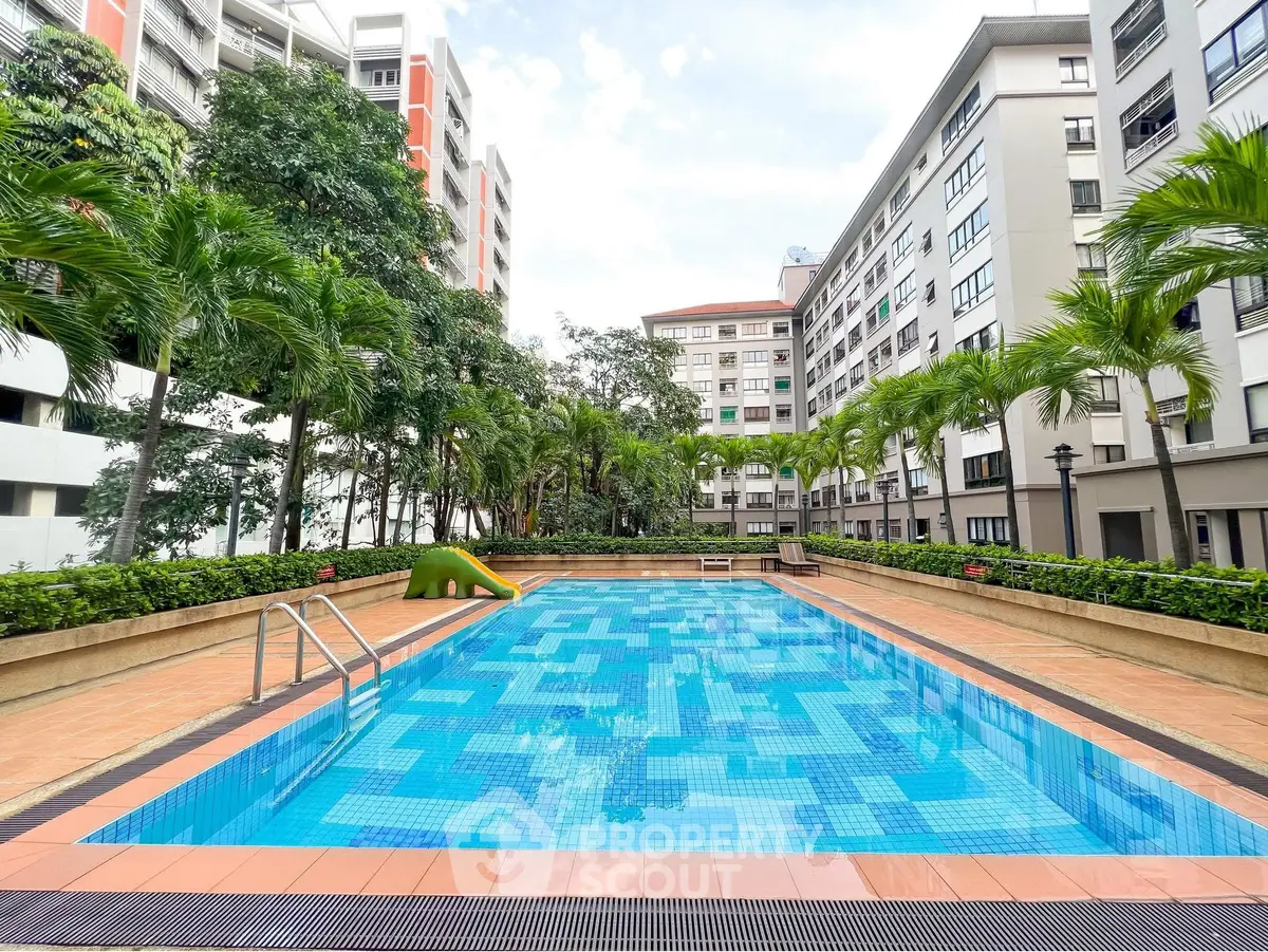 Luxurious residential complex with a pristine swimming pool surrounded by lush greenery and modern architecture.
