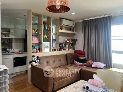 Cozy living room with brown sofa and open kitchen layout, featuring modern decor and ample natural light.