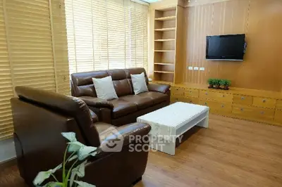 Elegant living room with leather sofas, wooden blinds, and wall-mounted TV in a cozy setting.