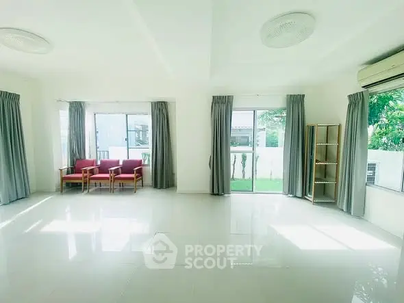 Spacious living room with large windows and garden view, perfect for natural light lovers.