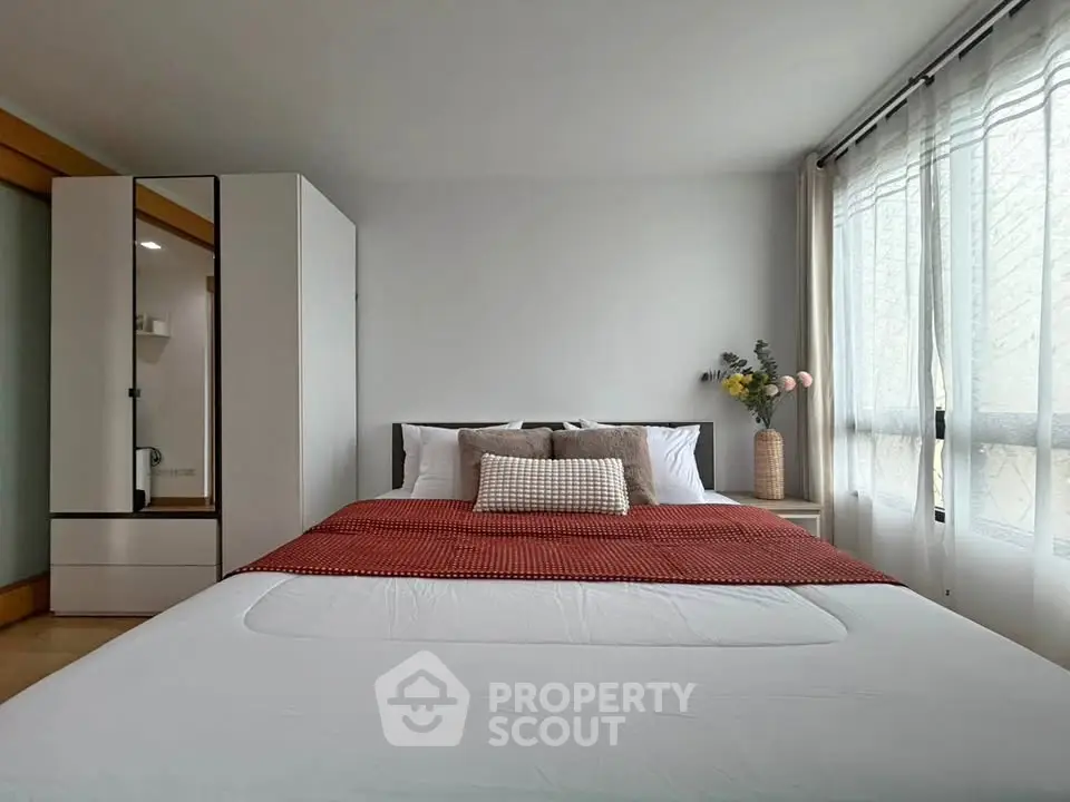 Spacious bedroom with modern decor and large window for natural light.