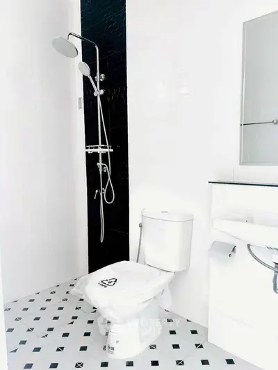 Modern bathroom with sleek black and white design, featuring a shower and toilet.