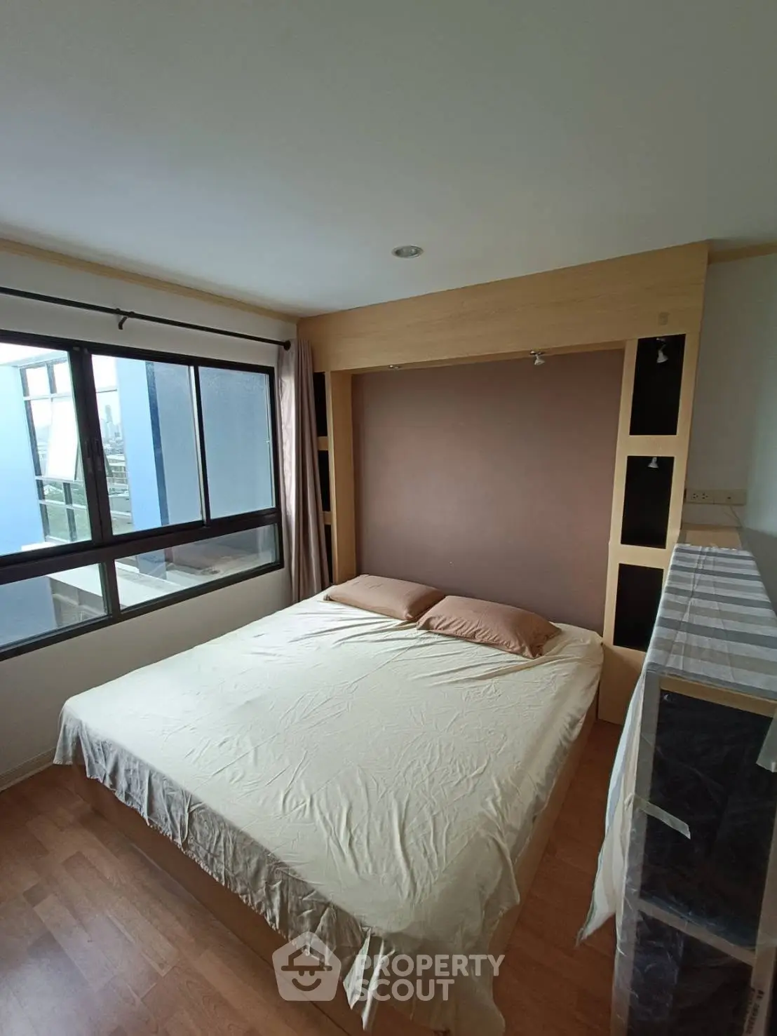 Spacious bedroom with large window and modern design in a cozy apartment.