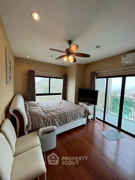 Spacious bedroom with large windows and balcony access, featuring modern decor and natural light.