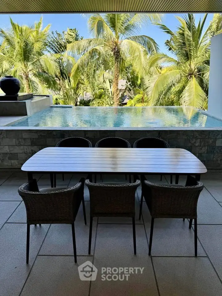 Luxurious outdoor dining area with pool and tropical garden view, perfect for relaxation and entertainment.