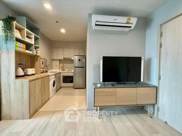 Modern open-plan living room with kitchen, featuring sleek appliances and stylish decor.