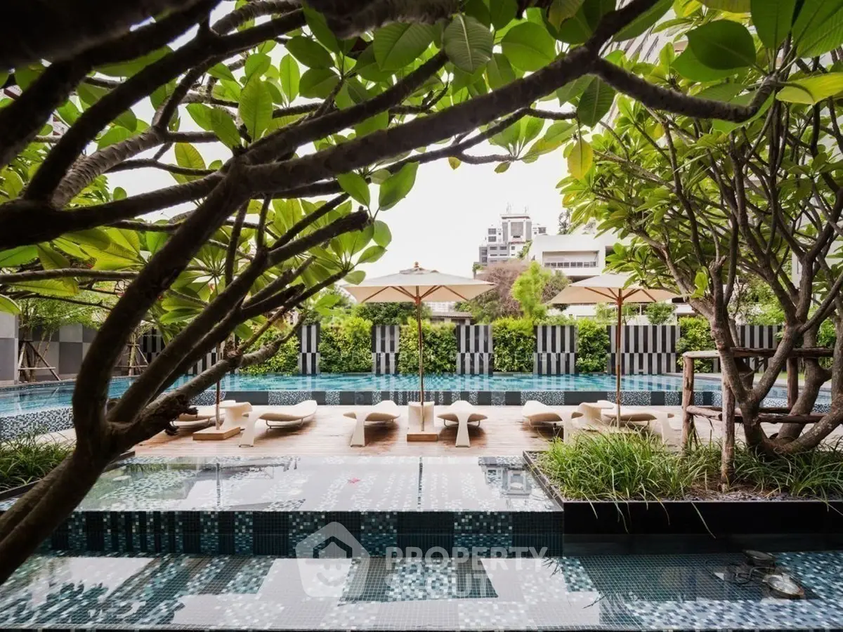 Luxurious outdoor pool area with lush greenery and stylish sun loungers, perfect for relaxation and leisure.
