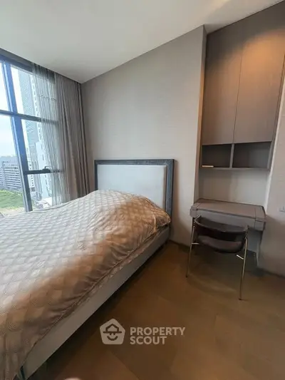 Modern bedroom with city view, featuring a stylish bed and compact study area, perfect for urban living.