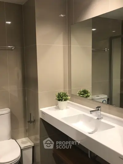 Modern bathroom with sleek fixtures and elegant design, featuring a large mirror and stylish sink.