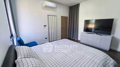Modern bedroom with large TV and air conditioning, featuring stylish decor and ample natural light.