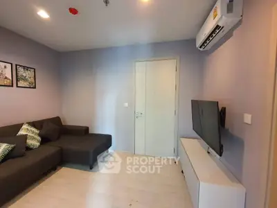 Modern living room with sleek sofa, wall-mounted TV, and air conditioning in a cozy apartment.