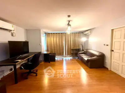 Spacious living room with modern furnishings and wooden flooring, ideal for comfortable living.