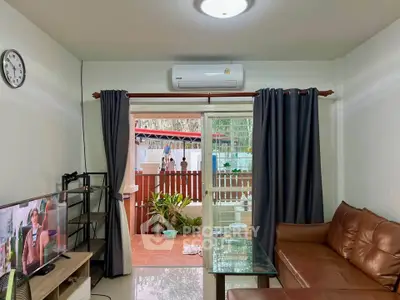 Cozy living room with leather sofa and garden view through sliding doors.