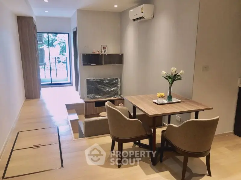 Modern living room with dining area and balcony view, featuring elegant furniture and natural light.