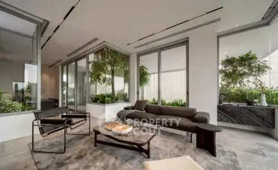 Luxurious modern living room with sleek furniture and lush greenery, perfect for relaxation.