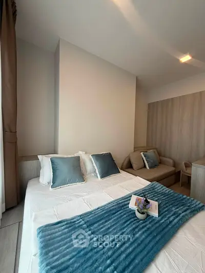 Modern bedroom with cozy decor and stylish furniture, featuring a plush blue throw and elegant cushions.