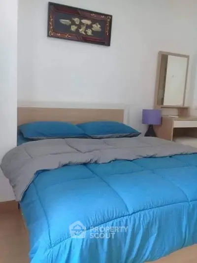 Cozy bedroom with blue bedding and modern decor, perfect for relaxation.