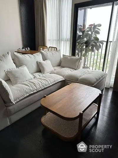 Elegant living room with plush sofa and modern coffee table, dark hardwood floors, and floor-to-ceiling windows inviting natural light.