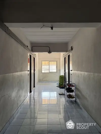 Spacious corridor with tiled flooring and natural light in residential building