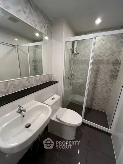 Modern bathroom with sleek design, featuring a glass shower enclosure and stylish tile accents.