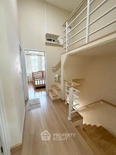 Spacious hallway with wooden flooring and modern staircase leading to a bright bedroom.
