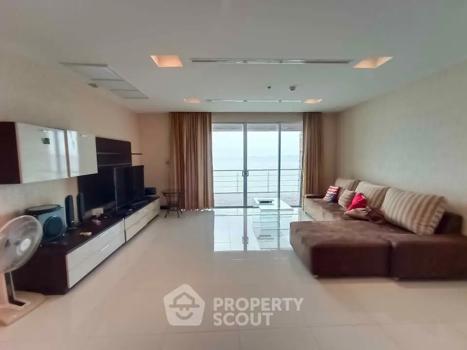 Spacious living room with modern decor and ocean view balcony in luxury apartment.