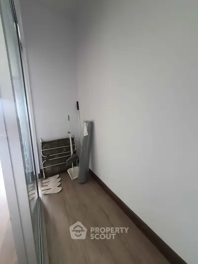 Compact storage area with wooden flooring and minimal furnishings, ideal for organizing household items.