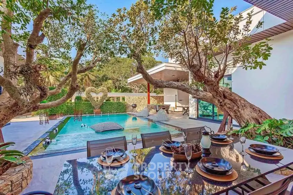 Luxurious outdoor pool area with elegant dining setup and lush greenery.