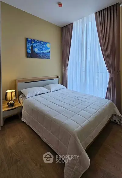 Cozy bedroom with large window and elegant curtains, featuring a comfortable bed and stylish decor.