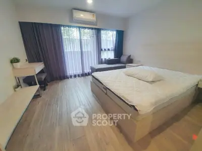 Spacious modern bedroom with large window and cozy seating area