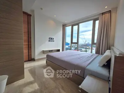 Modern bedroom with large windows offering city views and elegant wooden furnishings.