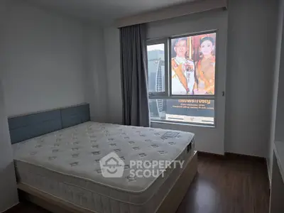 Spacious bedroom with large window and comfortable mattress in modern apartment.