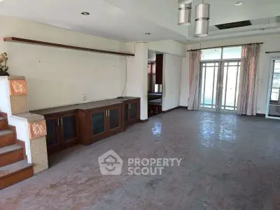 Spacious living room with large windows and built-in wooden cabinets, perfect for modern living.