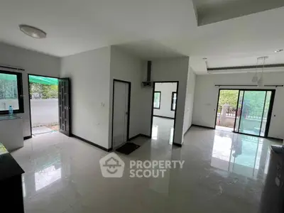 Spacious modern living room with large windows and balcony access, offering abundant natural light and serene views.
