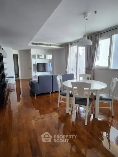 Spacious living room with wooden floors and modern furniture in a bright apartment.