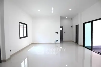 Spacious modern living room with sleek white tiles and large windows.