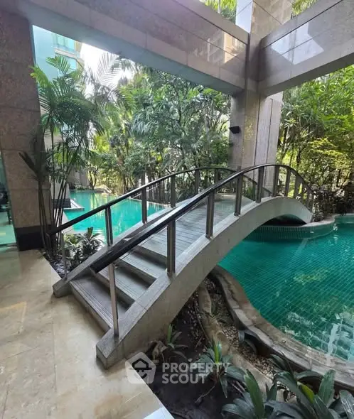 Luxurious indoor pool area with elegant bridge and lush greenery, perfect for relaxation and leisure.