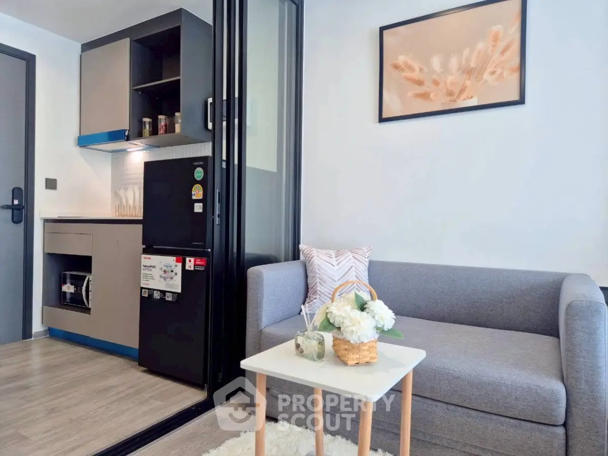 Modern living room with compact kitchen, stylish decor, and cozy seating area in a contemporary apartment.