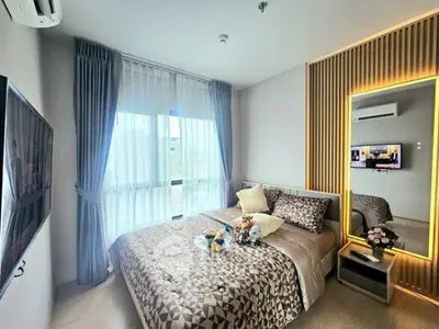 Modern bedroom with stylish decor, large window, and wall-mounted TV in a contemporary apartment.