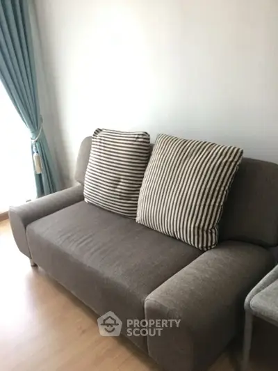 Cozy living room with stylish sofa and elegant curtains, perfect for relaxation.