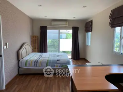 Spacious bedroom with modern decor and large windows for natural light.